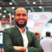 A Business man posing for aphoto wearing black blazers and white shirt